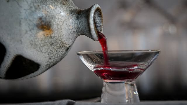 Sake pouring from a ceramic tokkuri into a footed glass